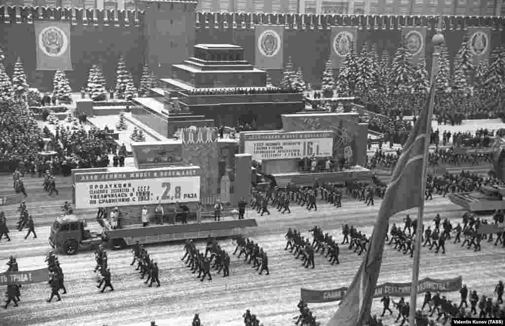Парад на Красной площади в 1970 году. Советские лидеры выстроились в ряд на смотровой площадке мавзолея. Мавзолей служил символическим ядром советской власти. Он был объектом множества нападений, включая взрыв террориста-смертника в 1973 году. Тогда погиб сам смертник и вошедшая вслед за ним в мавзолей пара. Тело Ленина, как сообщали, не пострадало от взрыва