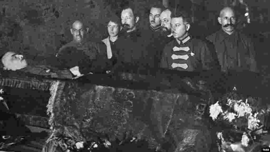 Большевистские начальники, в том числе Феликс Дзержинский (третий слева), печально известный основатель советской тайной полиции, организовавший множество массовых убийств, смотрят на тело Ленина. Конец января 1924 года После смерти Ленина разгорелись дискуссии о том, что делать с его телом. Иосиф Сталин настаивал на том, чтобы труп забальзамировали и выставили на всеобщее обозрение, заявив, что это "не будет противоречить старым русским обычаям". Лев Троцкий, ещё один лидер большевиков, отверг идею сделать из тела революционера реликвию. Сохранение трупа для публичного поклонения не имеет "ничего общего с марксизмом", возражал он