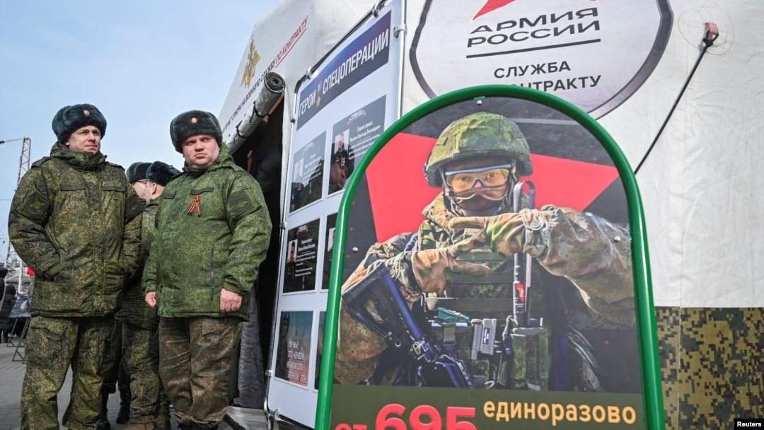 Ruski vojnici stoje u blizini mobilnog regrutnog centra s informativnim posterom o platama u Rostovu na Donu u Rusiji, mart 2024.