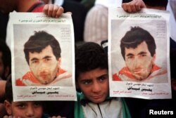 یک کودک فلسطینی، تصاویری از یحیی عیاش، از پایه‌گذاران شاخه نظامی حماس را در دست دارد