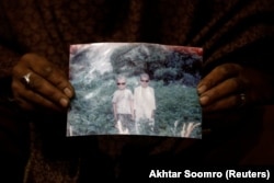 Захра Рамзан држи фотографија од нејзиниот 11-годишен син Али Мохамад (лево), кој беше однесен од водата.