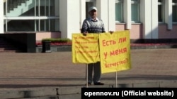 Удмуртський вчений Альберт Разін на пікеті біля будівлі Державної ради Удмуртії, після якого він здійснив самоспалення. Іжевськ, 10 вересня 2019 року. Поруч із ним виявили плакати, на одному з яких було написано: «І якщо завтра моя мова зникне, то я готовий сьогодні померти» 