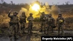 Українські військові позують для фото під час ведення вогню по російських позиціях із самохідної артилерійської установки на передовій у Харківській області, 24 грудня 2022 року