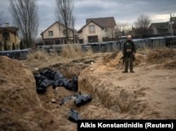На знімку від 6 квітня український військовий стоїть біля братської могили з тілами мирних жителів, загиблих під час російської окупації Бучі