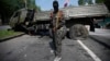 Пророссийский сепаратист стоит рядом с подорванным грузовиком у донецкого аэропорта. 29 мая 2014 года.