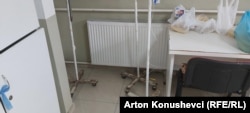 Kese sa voćem, sokom i hranom na stolu u bolesničkoj sobi. Pored stoje stari i zarđali stalci za infuziju.