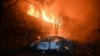 Un automobil incendiat este surprins în fața unei case în flăcări, după un atac cu dronă rusă la Harkov, pe 11 iunie 2025, în contextul invaziei ruse în Ucraina.