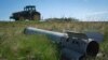 Dio ruske rakete na zemlji dok poljoprivrednik obrađuje svoje polje u ratom razorenoj Harkivskoj oblasti, Ukrajina, april 2024.