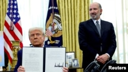 Američki predsednik Donald Tramp pokazuje potpisanu izvršnu naredbu o povećanju carina u prisustvu ministra trgovine Hauarda Lutnika u Vašingtonu, SAD, februar 2025.