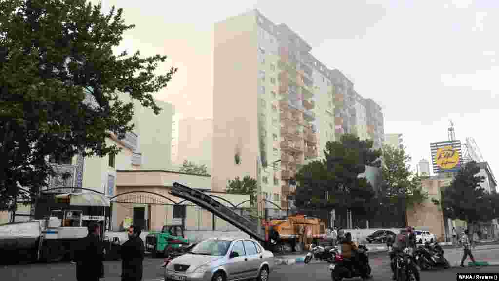 Oamenii se adună în jurul unei clădiri avariate în urma loviturilor aeriene israeliene asupra Teheranului.