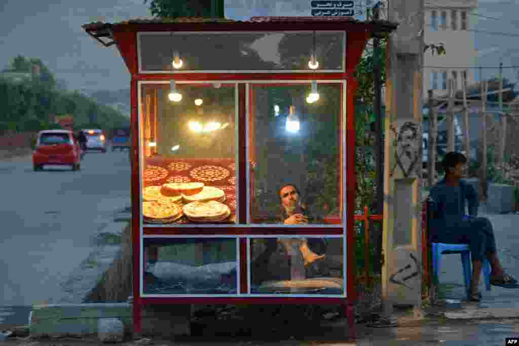 یک فروشنده افغان که نان میفروشد، در کنار خیابانی در منطقهٔ فیضآباد، ولایت بدخشان، منتظر مشتری است
