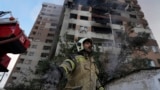 Израильдің Иранға әуе шабуылынан бүлінген көпқабатты тұрғын үйдің қасында тұрған өрт сөндіруші. Тегеран, 13 маусым, 2025 жыл.