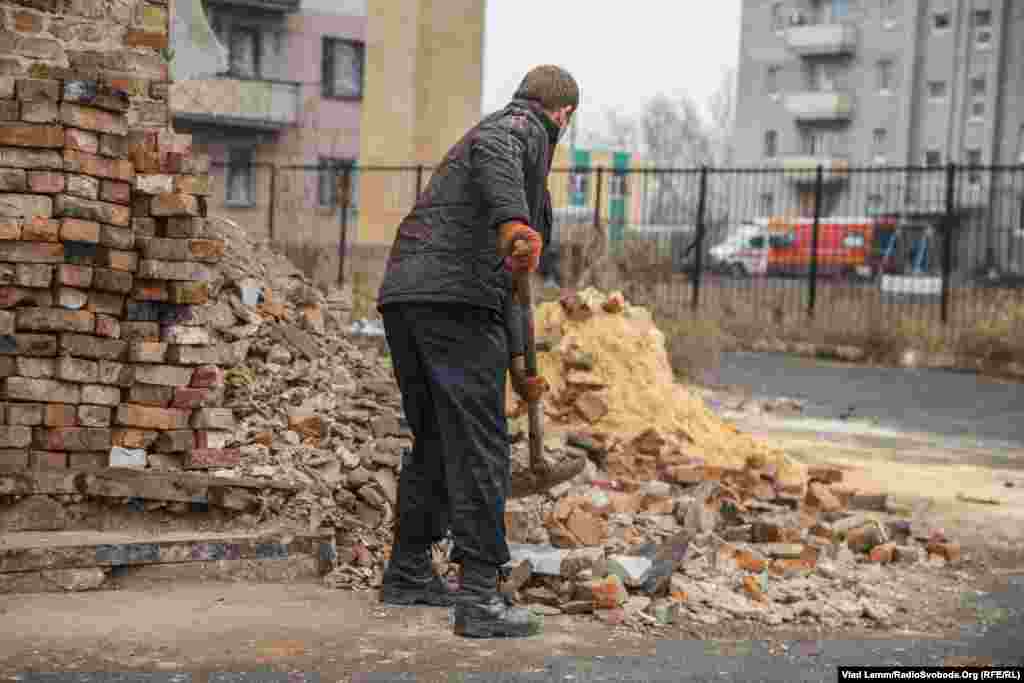 Незважаючи на звук вибухів зі сторони селища Опитне, комунальники прибирають листя з вулиць. А цей місцевий житель прибирає залишки битої цегли