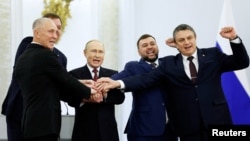 Президент Росії Володимир Путін і Денис Пушилін, Леонід Пасечник, Володимир Сальдо, Євген Балицький, яких призначили керувати частинами окупованих Донецької, Луганської, Херсонської та Запорізької областей України, на церемонії проголошення анексії цих територій у Кремлі. 