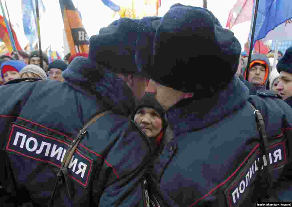 Жена гледа во полицајци за време на концертот на Црвениот плоштад по повод втората годишнина од руската анексија на Крим, Москва 18.03.2016. 