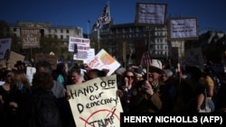 Луѓе држат транспаренти за време на протестот против американскиот претседател Доналд Трамп и неговиот советник Илон Маск во центарот на Лондон на 5 април 2025 година, како дел од Меѓународниот ден на протести наречени „Рацете настрана!“.